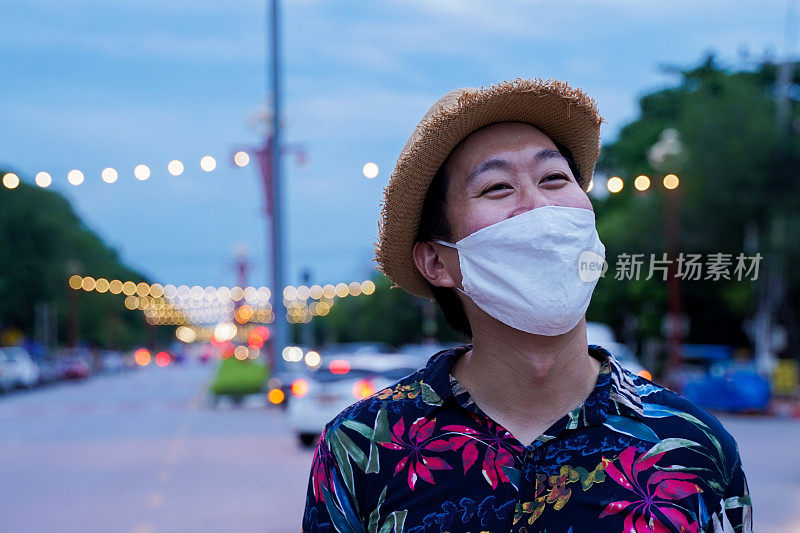 Asian man smiling behind a protective face mask travelling to Thailand street while wearing a protective mask to prevent from coronavirus Covid-19